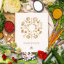Flat lay of vegetables surrounding a cookbook